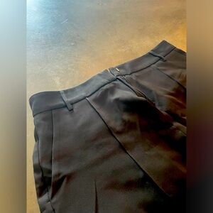 Black pleated, knee-length, high waisted shorts.